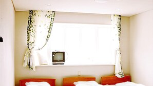 A bedroom with a bed, a window with curtains, and a television on a small table. - Goishigahama House (Shimoda)