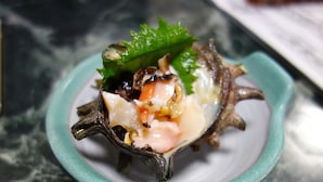 A dish of food served on a small plate with a green rim, placed on a marble surface. - Goishigahama House (Shimoda)