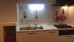 A compact kitchen with a sink, stove, and cabinets. - Minhouses (Kyoto)