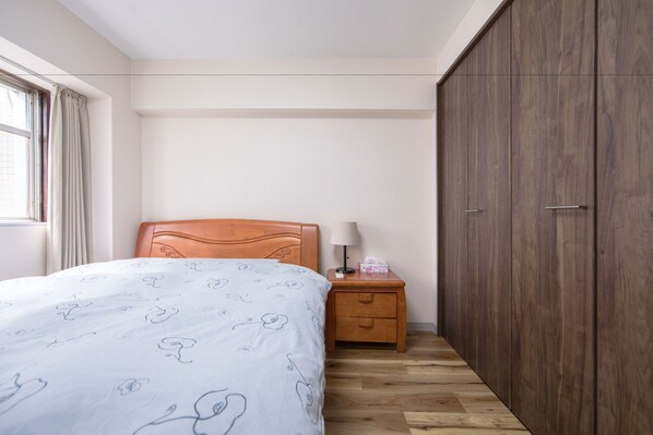 A bedroom with a bed, wooden nightstand, and wardrobe.