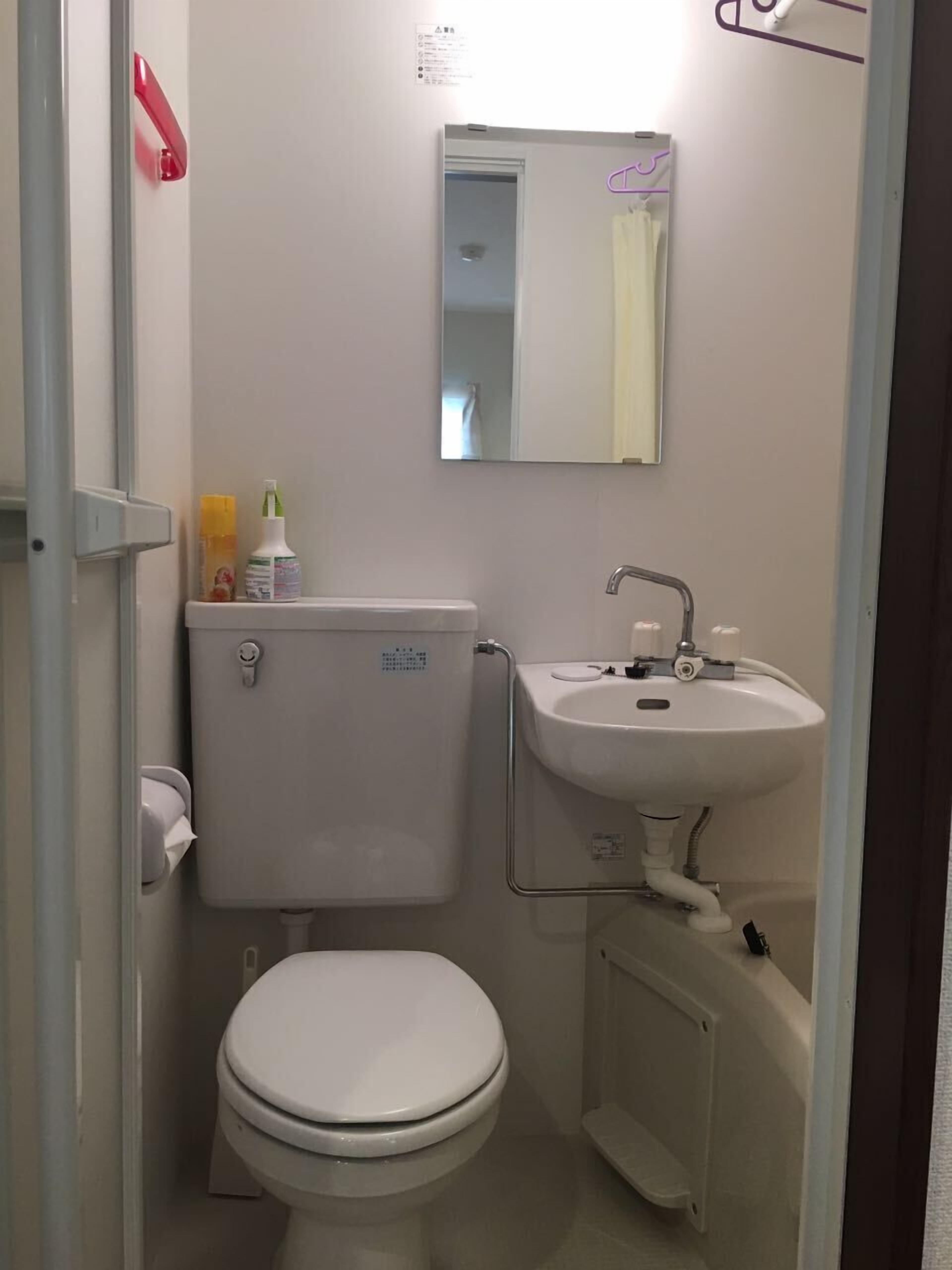 Casa de banho pequena e compacta com sanita, lavatório e espelho.