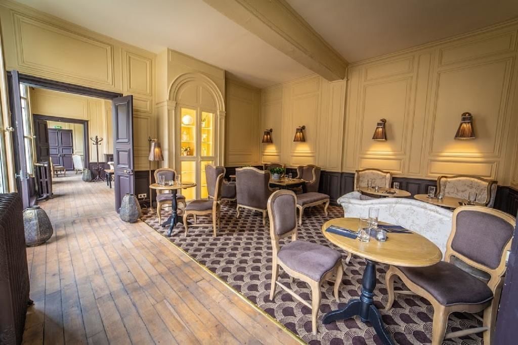 Un hall d’hôtel doté d’un sol à motifs, d’un espace détente avec des tables et des chaises, et d’un éclairage mural.