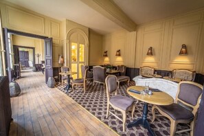 A hotel lobby with a patterned floor, seating area with tables and chairs, and wall-mounted lighting. - Hotel Particulier de Champrond (Chartres)