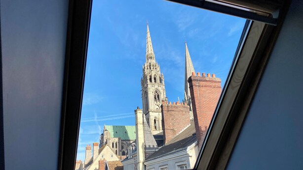 A view through a skylight of a Gothic-style church tower and adjacent buildings. - Hotel Particulier de Champrond (Chartres)