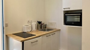 Una cocina compacta con tostadora, hervidor, lavamanos y horno empotrado.