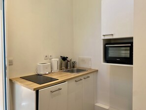 A compact kitchen with a toaster, a kettle, a sink, and a built-in oven.