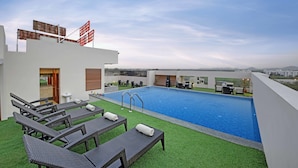 Una piscina en la azotea con sillones de descanso y vistas a la ciudad.