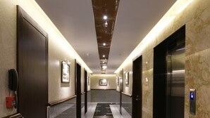 Un corredor de hotel moderno con paredes de mármol, suelo pulido e imágenes enmarcadas.