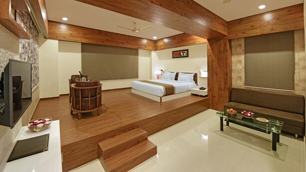 Un dormitorio moderno con techo de madera, una cama, una mesita de centro de vidrio y una zona de estar.