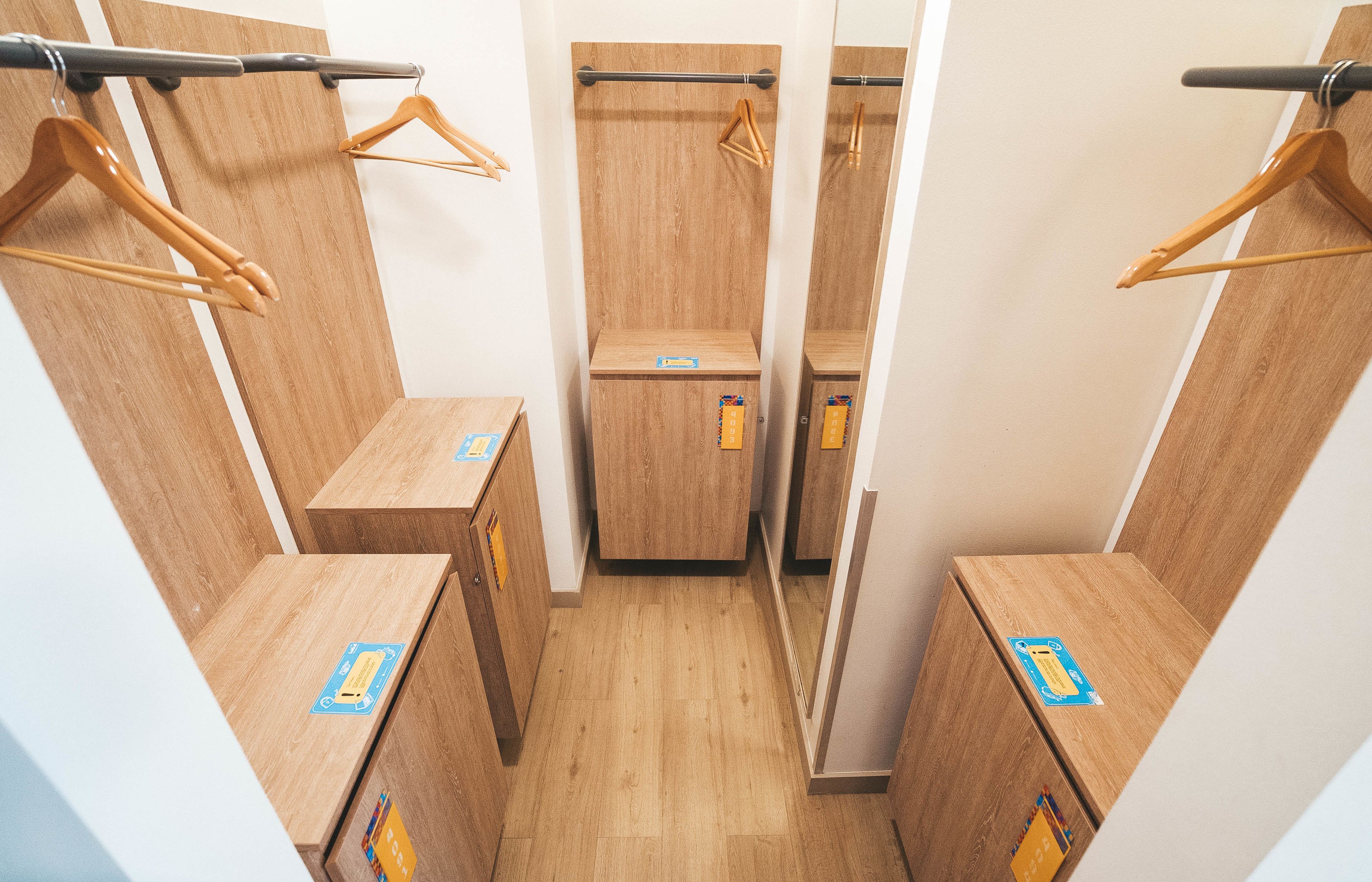 A narrow walk-in closet with wooden cabinets and wooden hangers on metal rods.