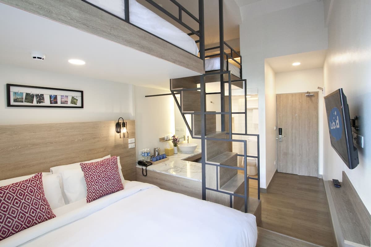 Quarto de hotel moderno com uma cama, banheiro com pia e escada.