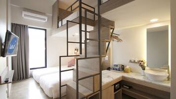 A modern hotel room with a bunk bed, a bathroom with a large mirror, and a desk with a TV.