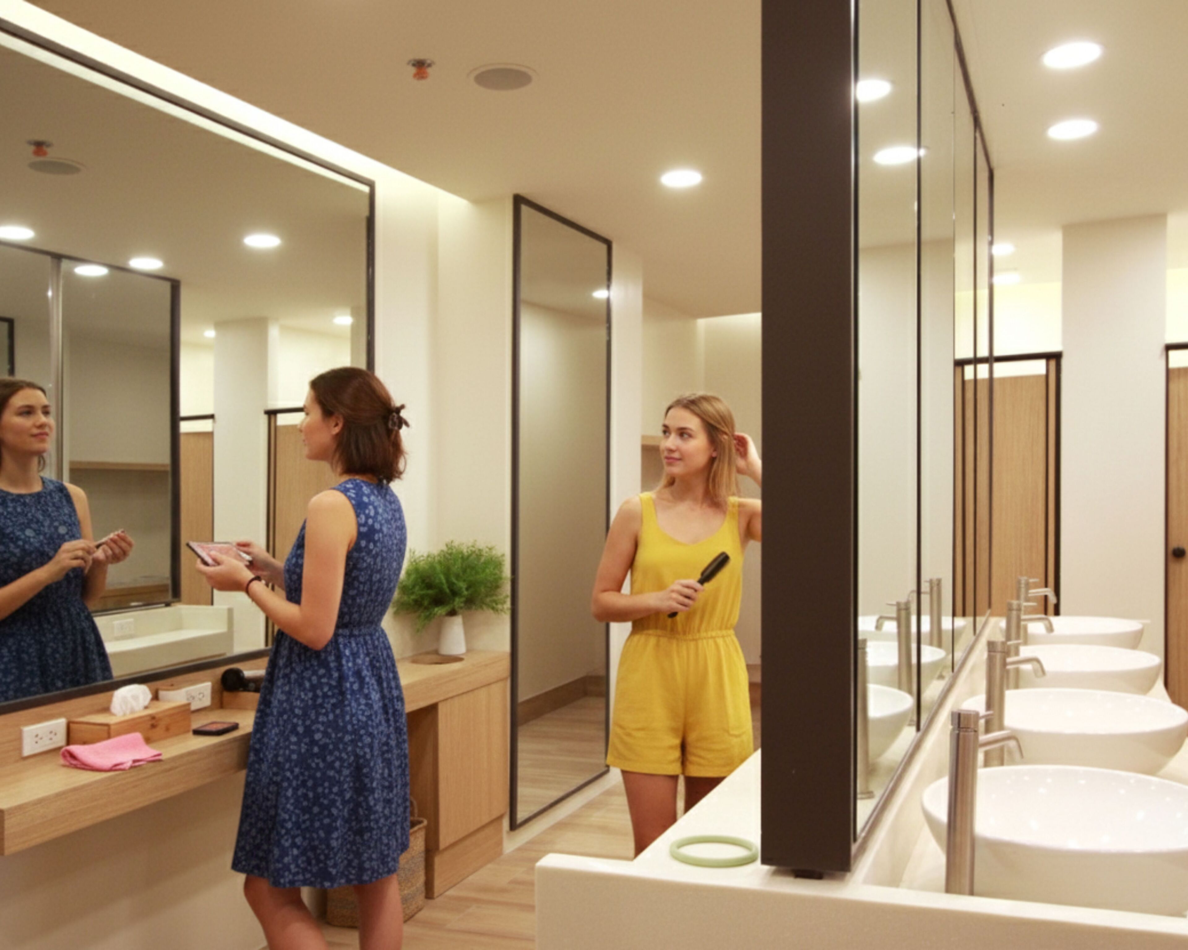 A modern bathroom with a large mirror, wooden vanity, and multiple sinks.