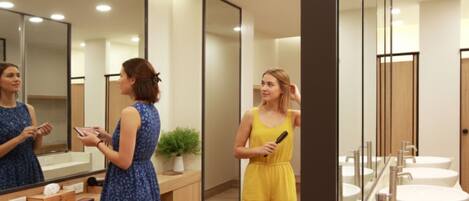 A modern bathroom with a large mirror, wooden vanity, and multiple sinks.