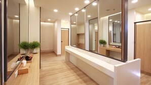 A modern bathroom with a long counter, mirrors, and potted plants.