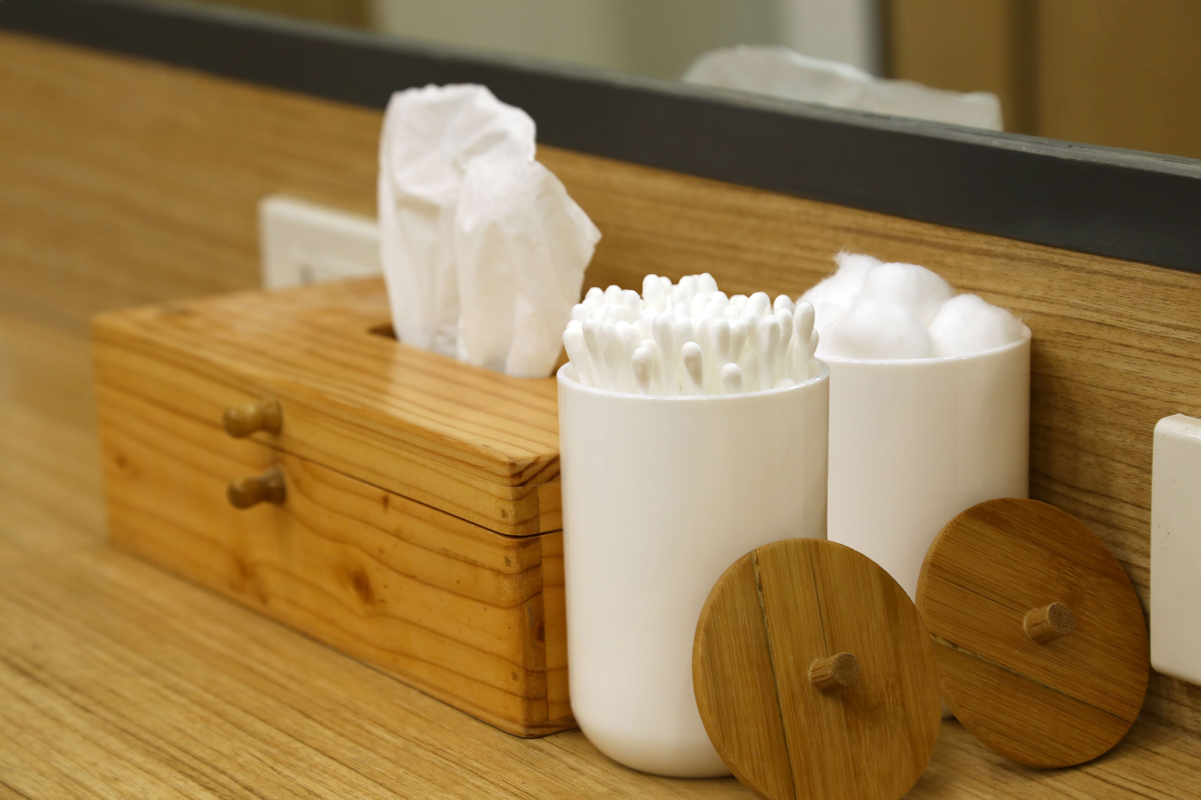 A wooden chest with tissue boxes and cotton swabs on a wooden surface.