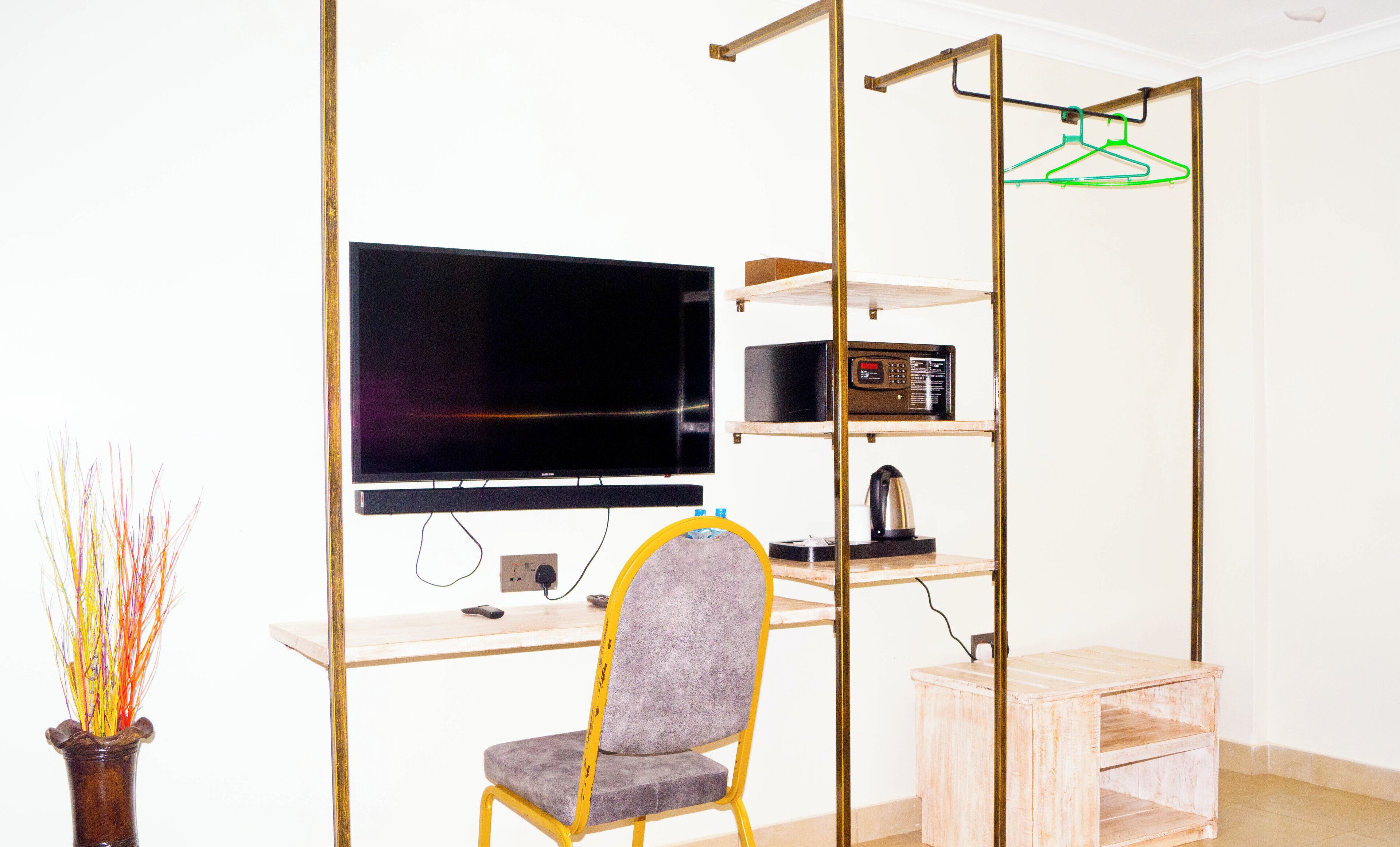 Un espacio habitable compacto con televisión de pantalla plana, una kitchenette pequeña y una silla.