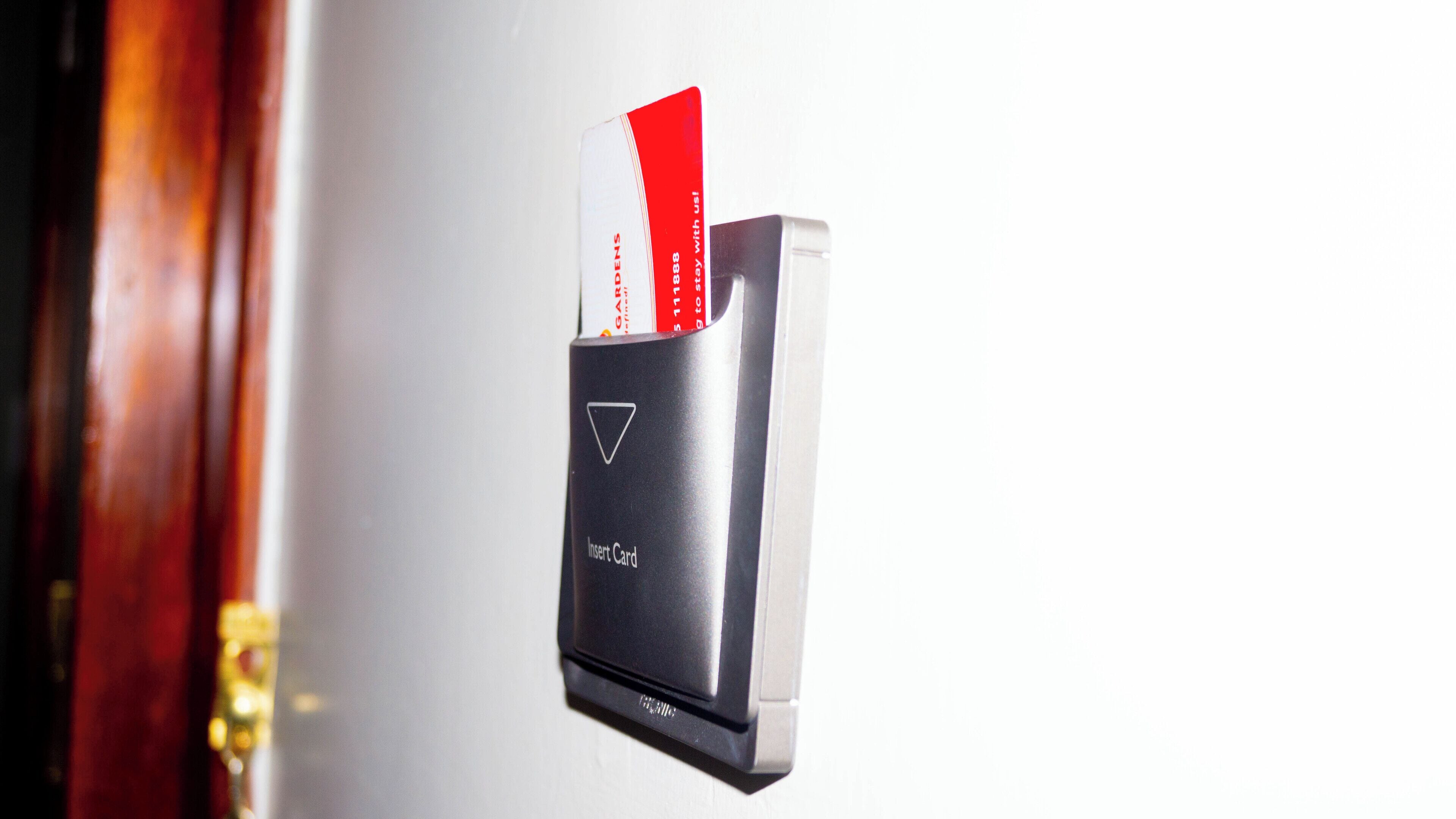 Lector de tarjetas con una tarjeta roja insertada, posiblemente para acceso o pago.