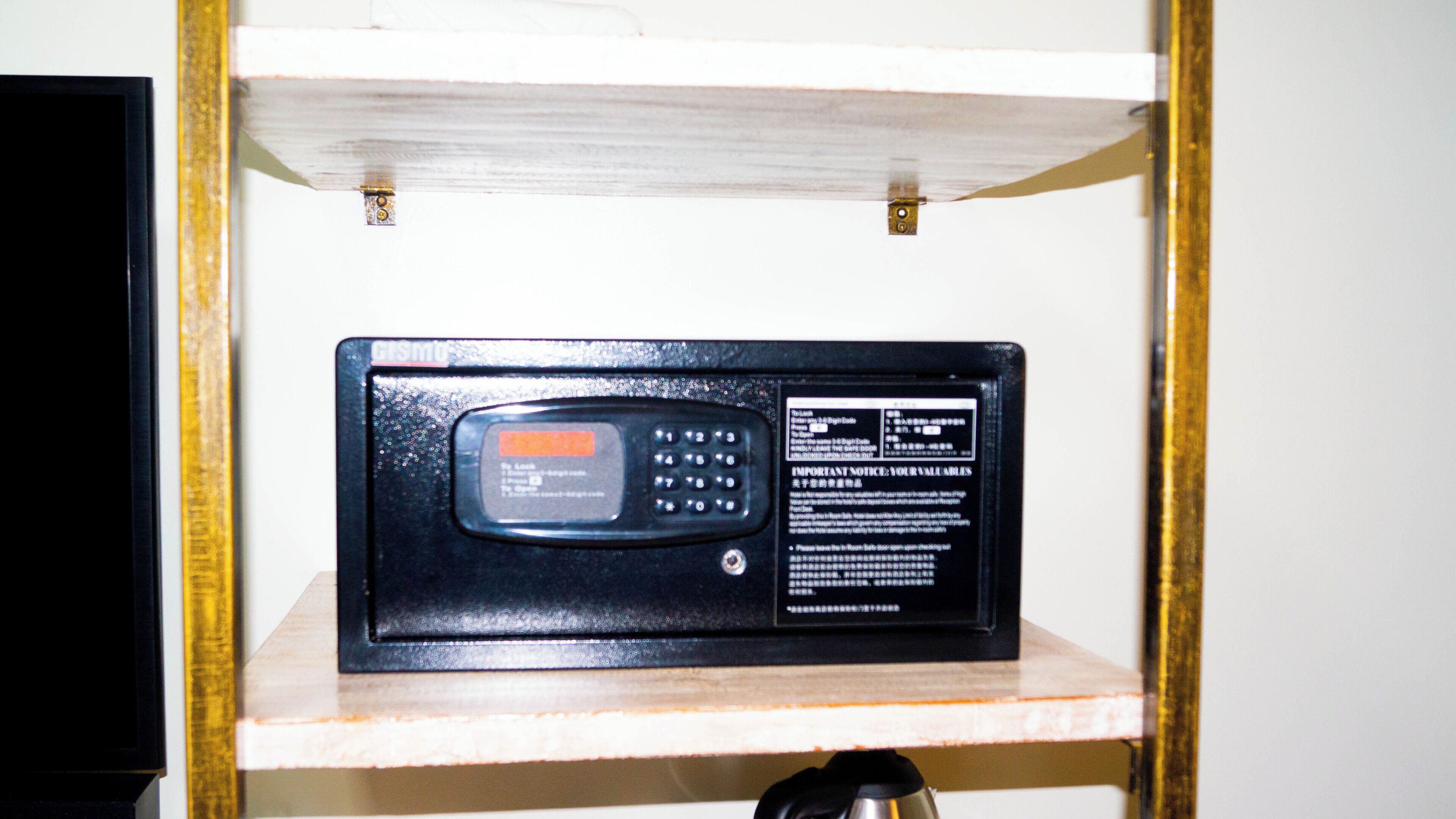 A black electronic device with a keypad and a screen, mounted on a wooden shelf.