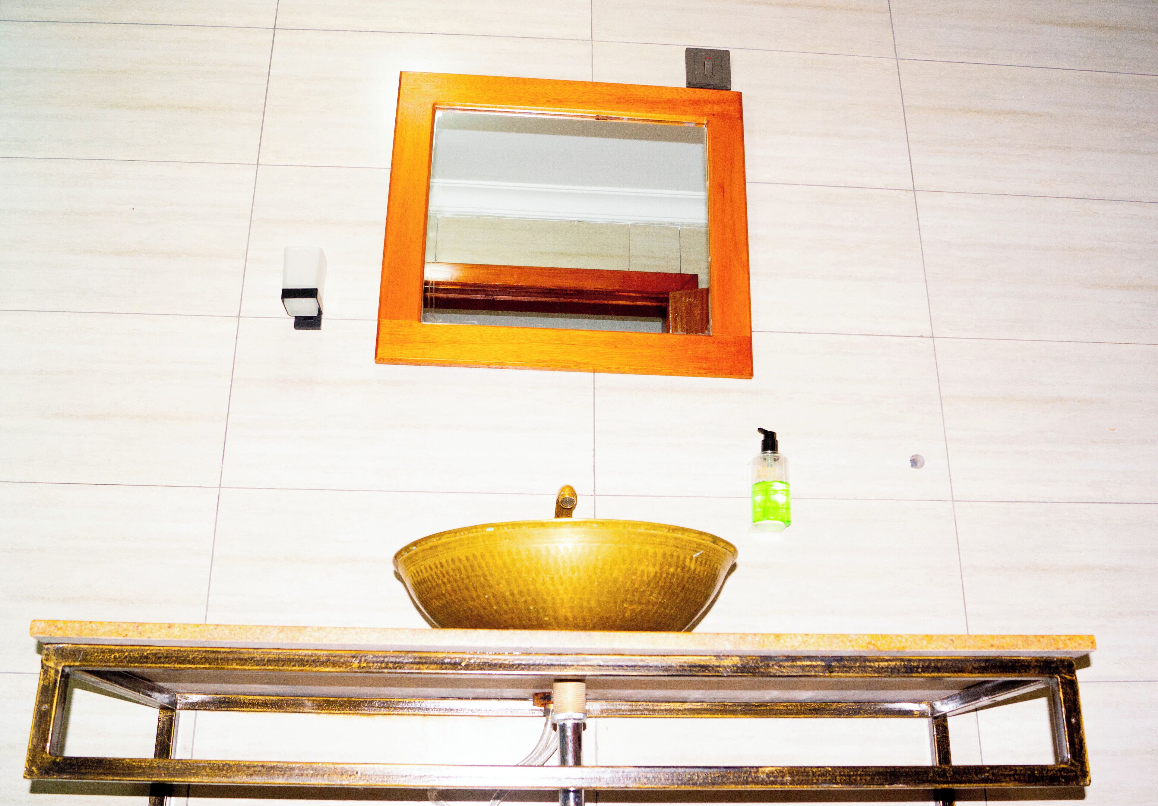 A bathroom with a large mirror, a sink with a bowl, and a soap dispenser.