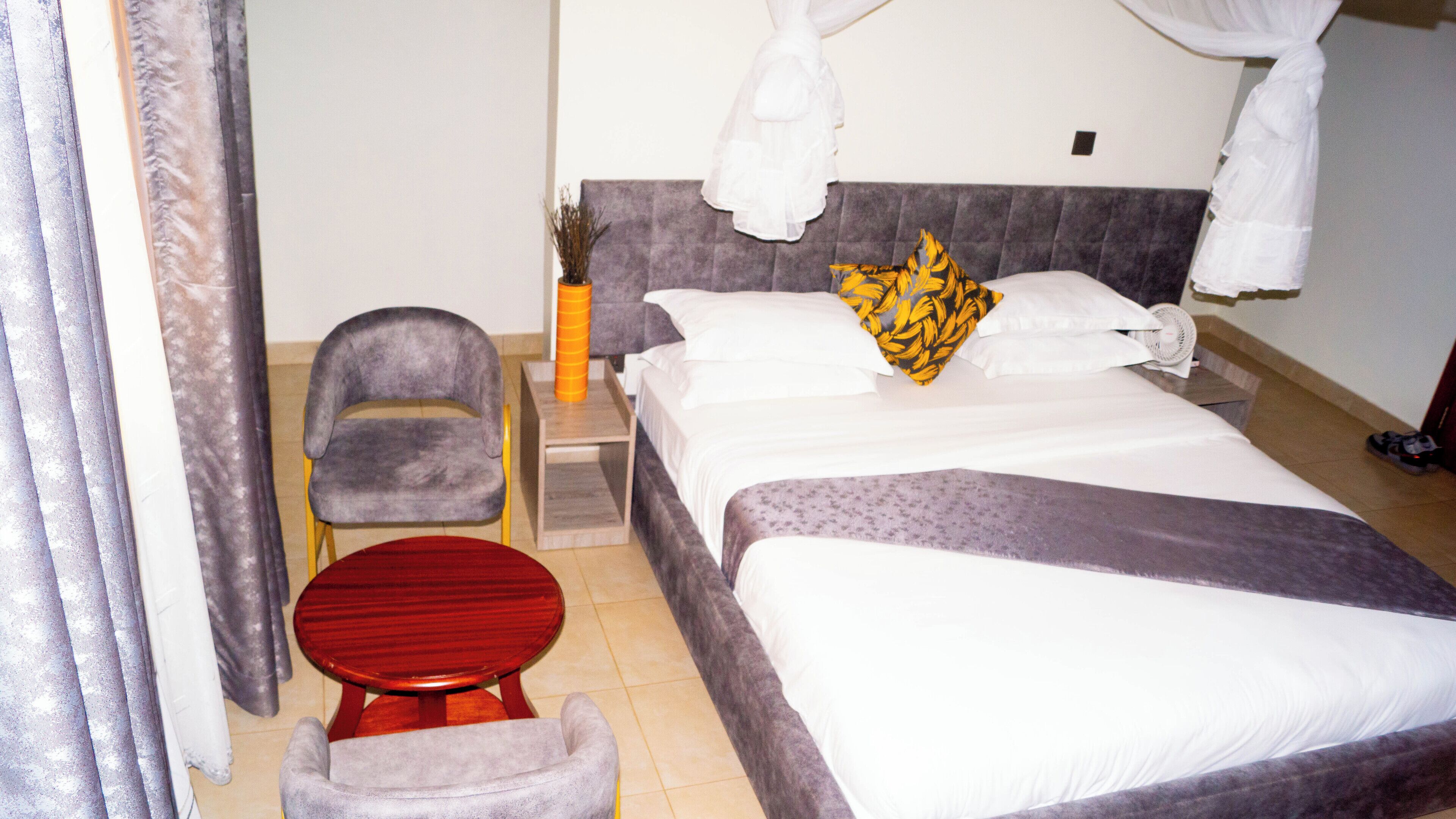 Une chambre d’hôtel avec un lit, une chaise, une petite table et une table de chevet.