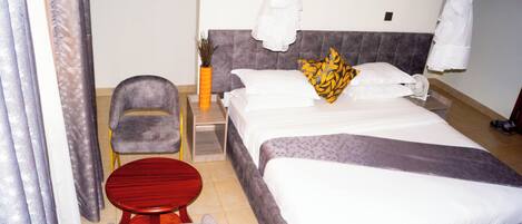 Une chambre d’hôtel avec un lit, une chaise, une petite table et une table de chevet.