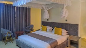 Een hotelkamer met een groot bed, twee stoelen, een kleine tafel en een nachtkastje.