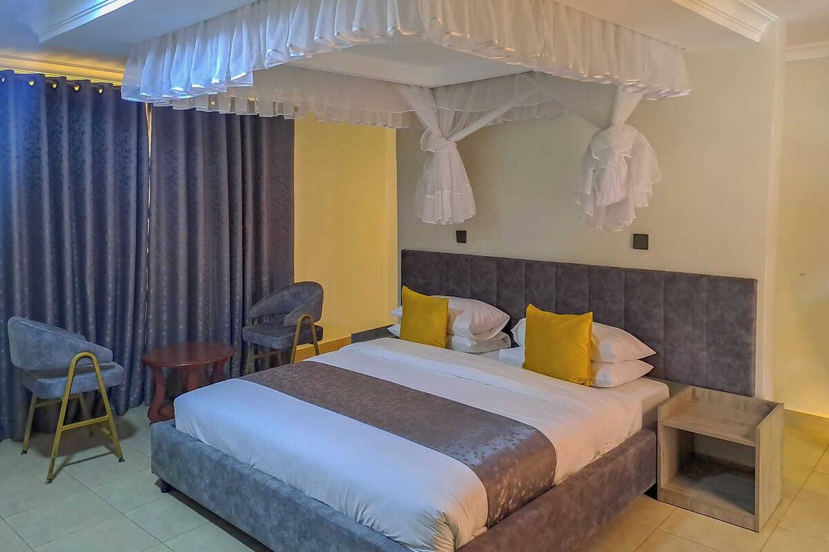 Une chambre d’hôtel avec un grand lit, deux chaises, une petite table et une table de chevet.