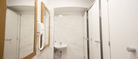 A bathroom with a marble sink, a hand dryer, and a mirror with a wooden frame.