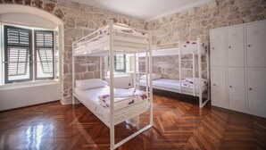 A room with two bunk beds, a stone wall, wooden flooring, and a set of lockers. - Hostel Angelina Old town Dubrovnik (Dubrovnik)