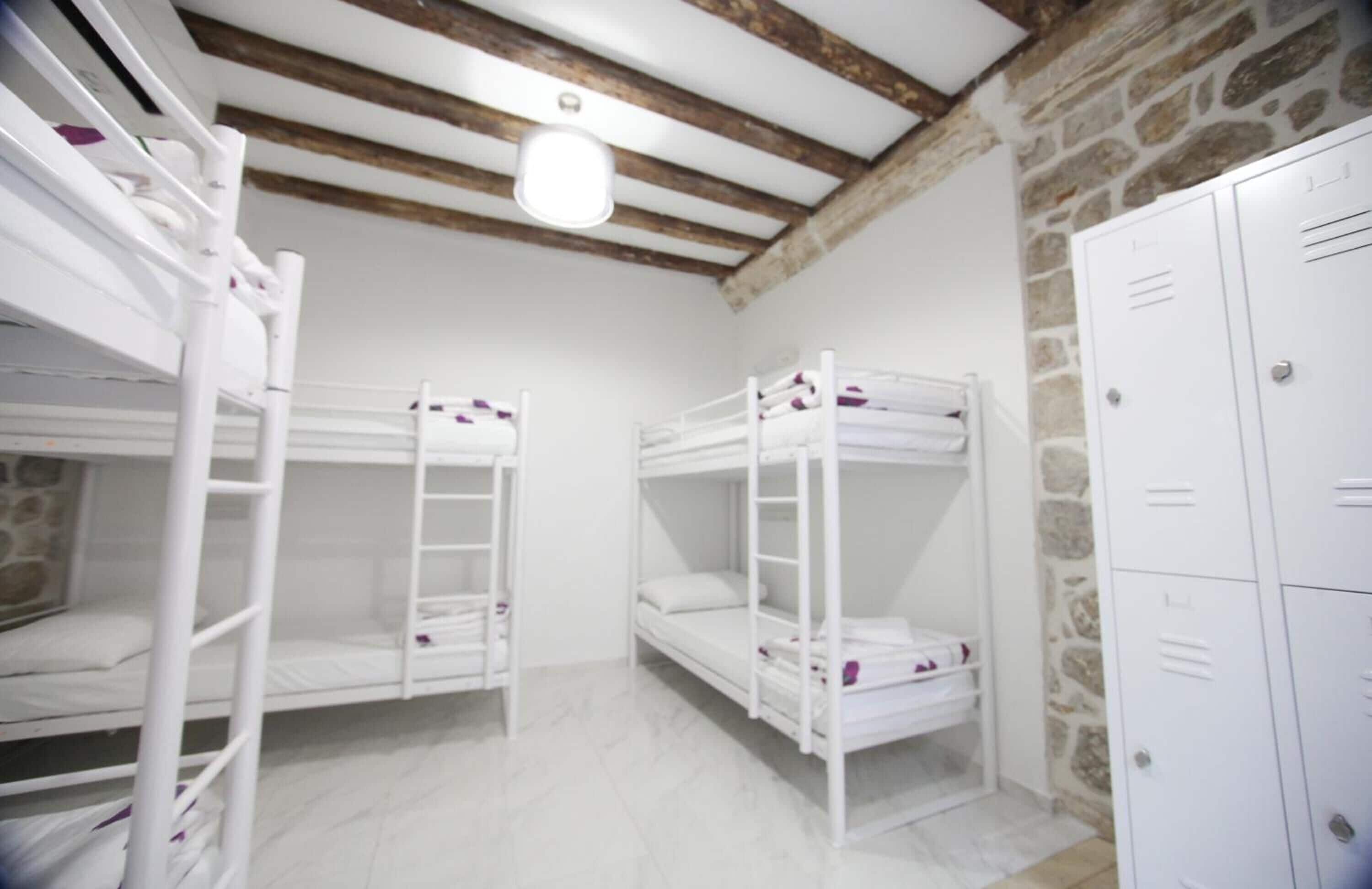 A room with bunk beds, a stone wall, and white lockers.