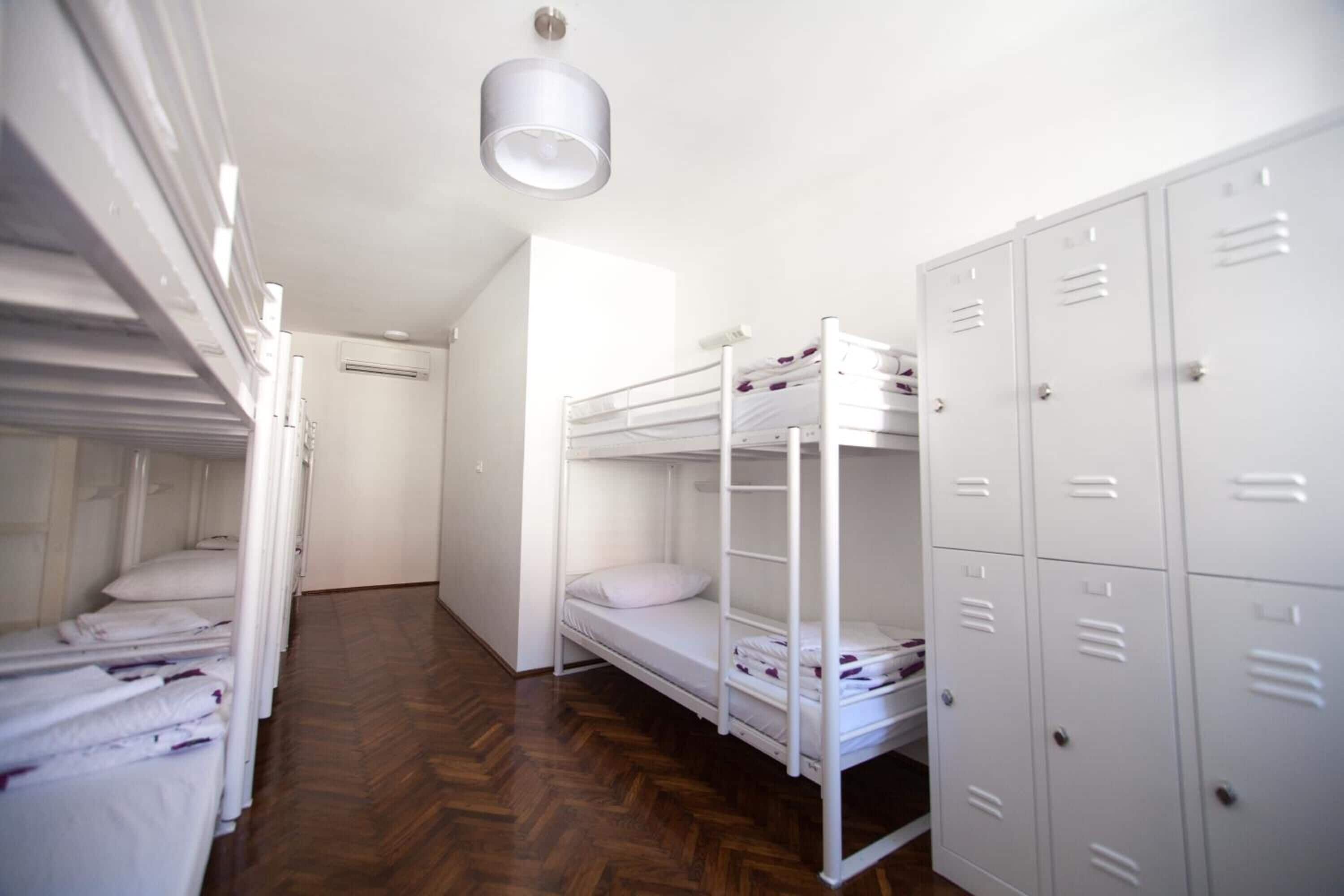 A dormitory room with bunk beds, a wardrobe, and a ceiling light.