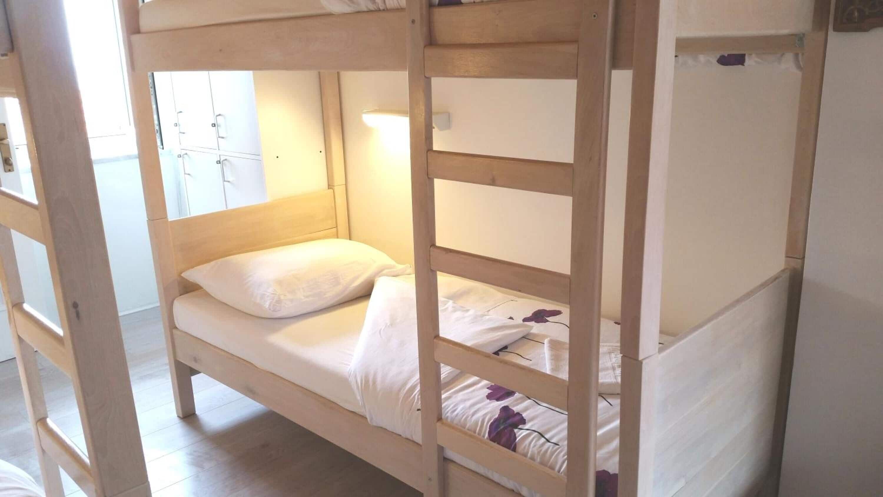 A bunk bed with white bedding and a wooden frame.