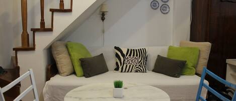 A cozy living area with a sofa, a small round table, and a staircase.