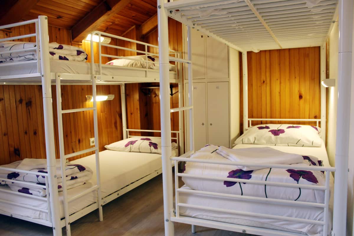 A bunk bed room with wooden walls and a bunk bed with a white frame.