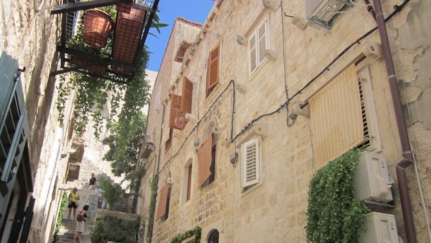 A narrow stone staircase leading up to a building with multiple windows, some with shutters, and air conditioning units attached to the exterior walls. - Hostel Angelina Old town Dubrovnik (Dubrovnik)