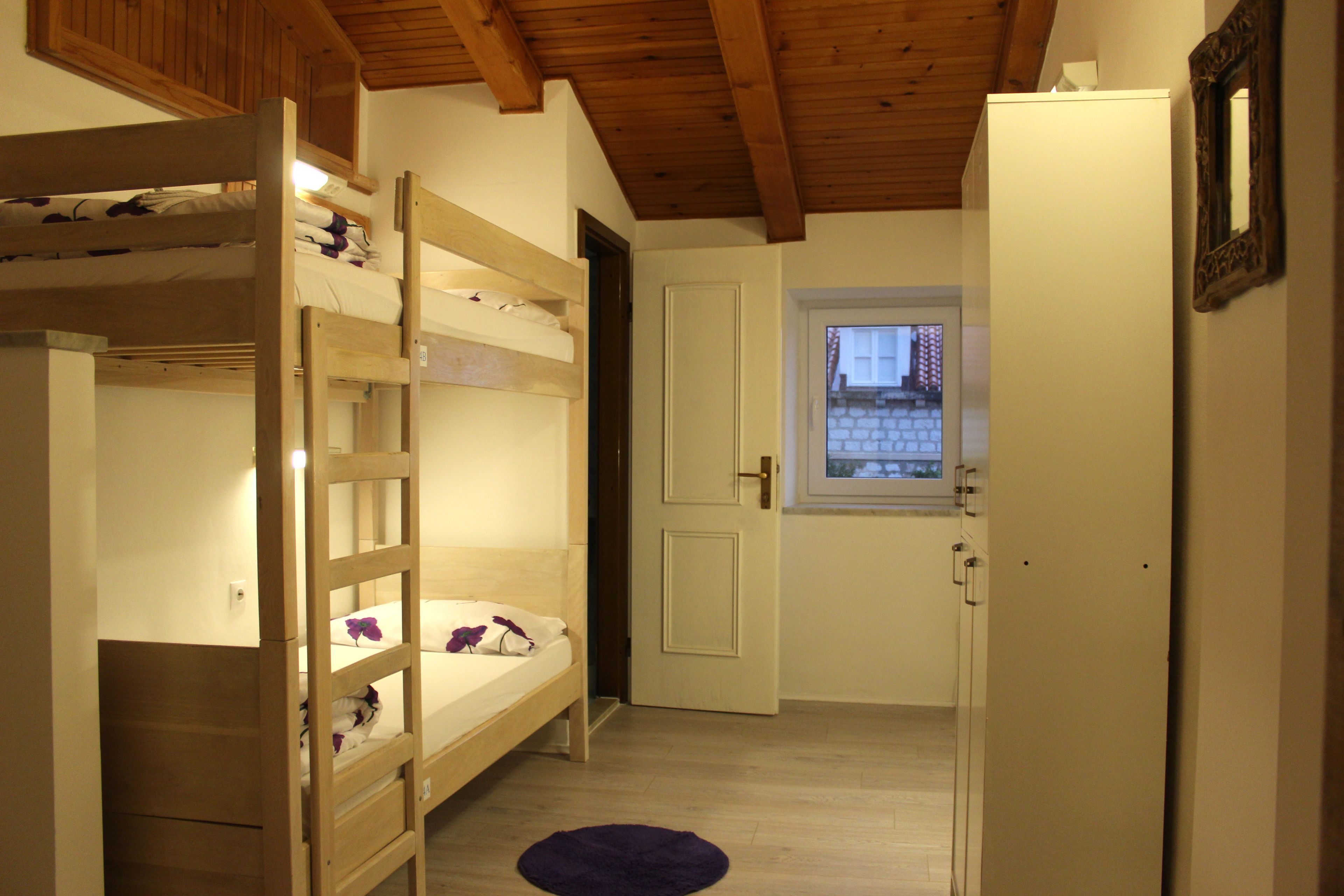 A bunk bed room with a wooden ceiling, a door leading to a balcony, and a small window.