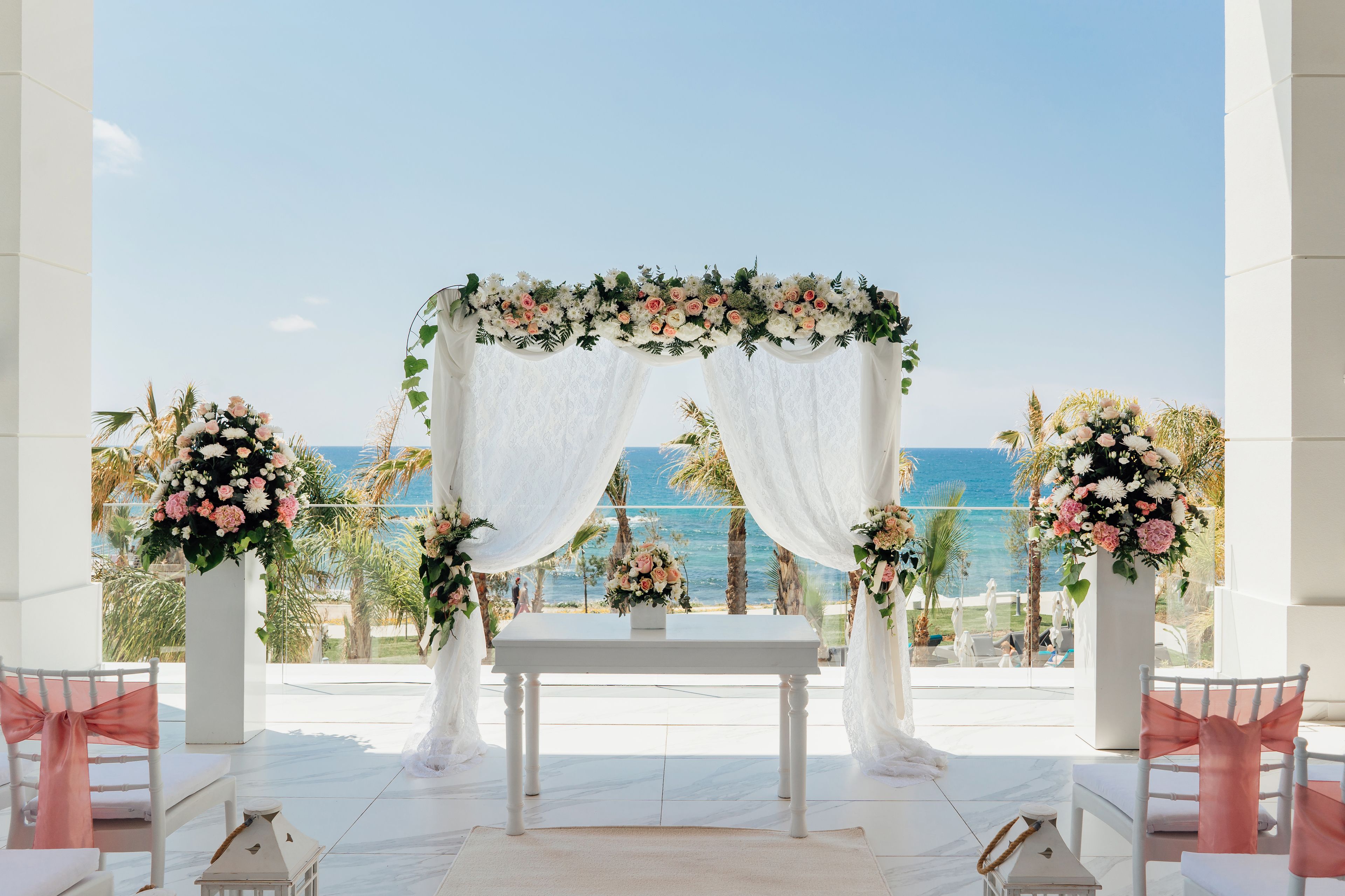 An outdoor wedding ceremony setup with a white altar, floral decorations, and a view of the ocean.