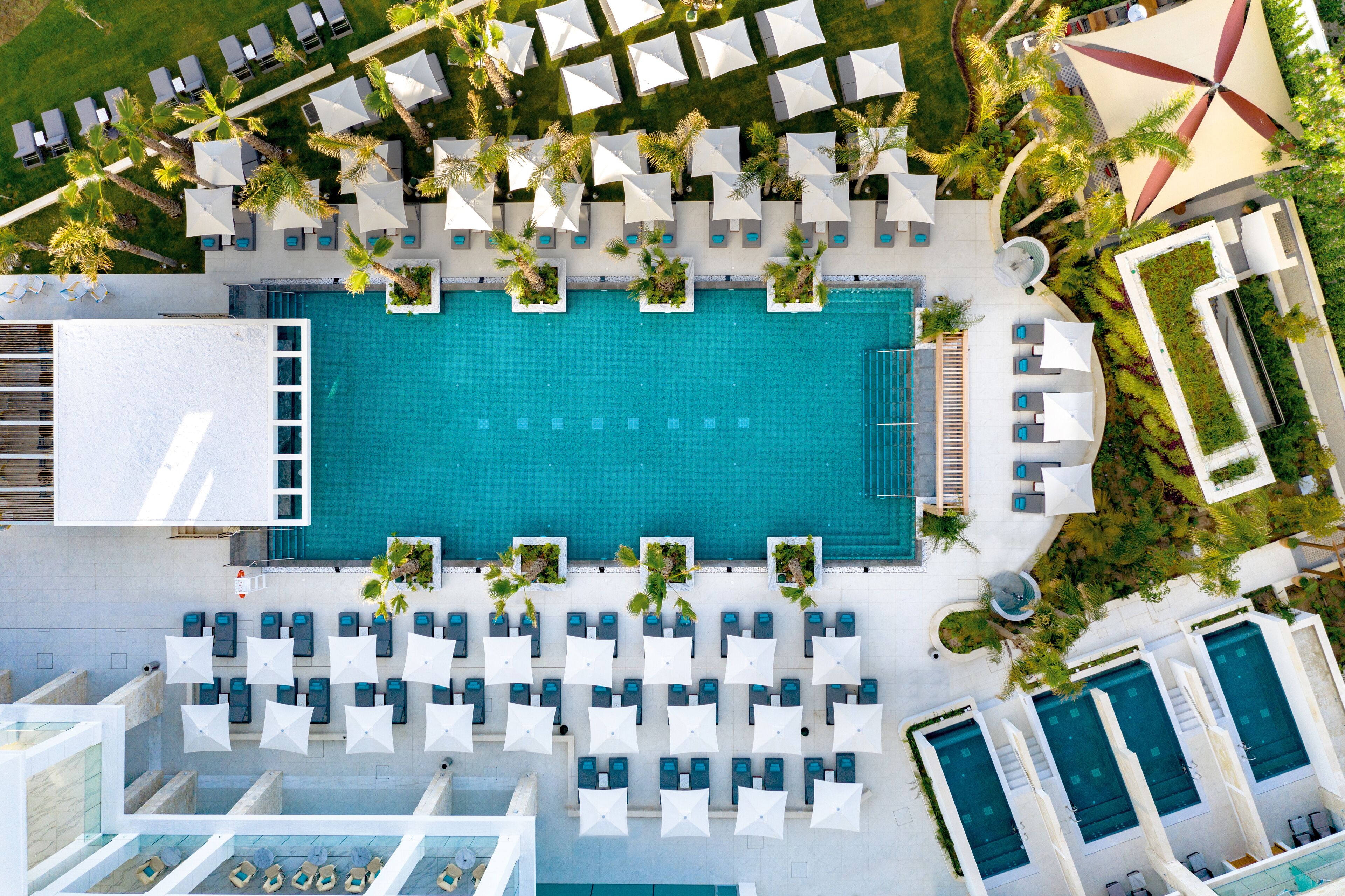 An aerial view of a resort with multiple swimming pools, sun loungers, and umbrellas.