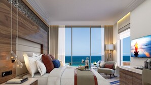 A modern hotel room with a large bed, a TV, a desk, and a view of the ocean. - Amavi, MadeForTwo Hotels - Paphos (Paphos)