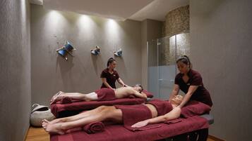 Un cuarto de terapia de masajes con tres clientes recibiendo tratamientos.