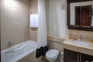 A bathroom with a bathtub, toilet, sink, and a mirror.