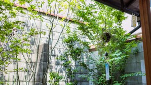 Un jardín japonés tradicional con muros de piedra, bambú y adornos colgantes.