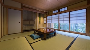 Una habitación japonesa tradicional con suelo de tatami, una mesa de madera baja y puertas correderas shoji.
