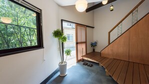 Un pasillo con un banco de madera, una planta en maceta y vistas al exterior con vegetación.