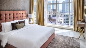 A modern hotel room with a large bed, a city view, and a desk with a lamp. - Luxury Staycation - Continental Tower (Dubai)