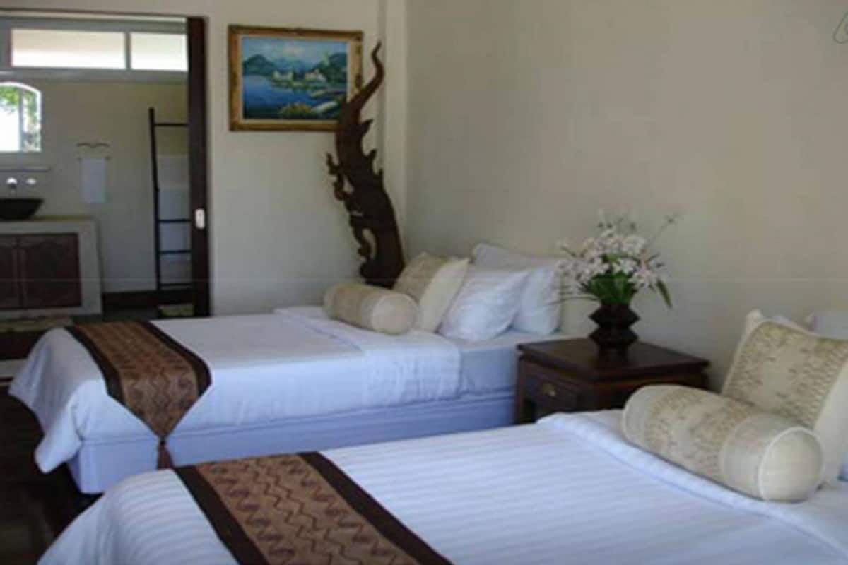 A hotel room with two beds, a painting on the wall, a wooden cabinet, and a vase with flowers.