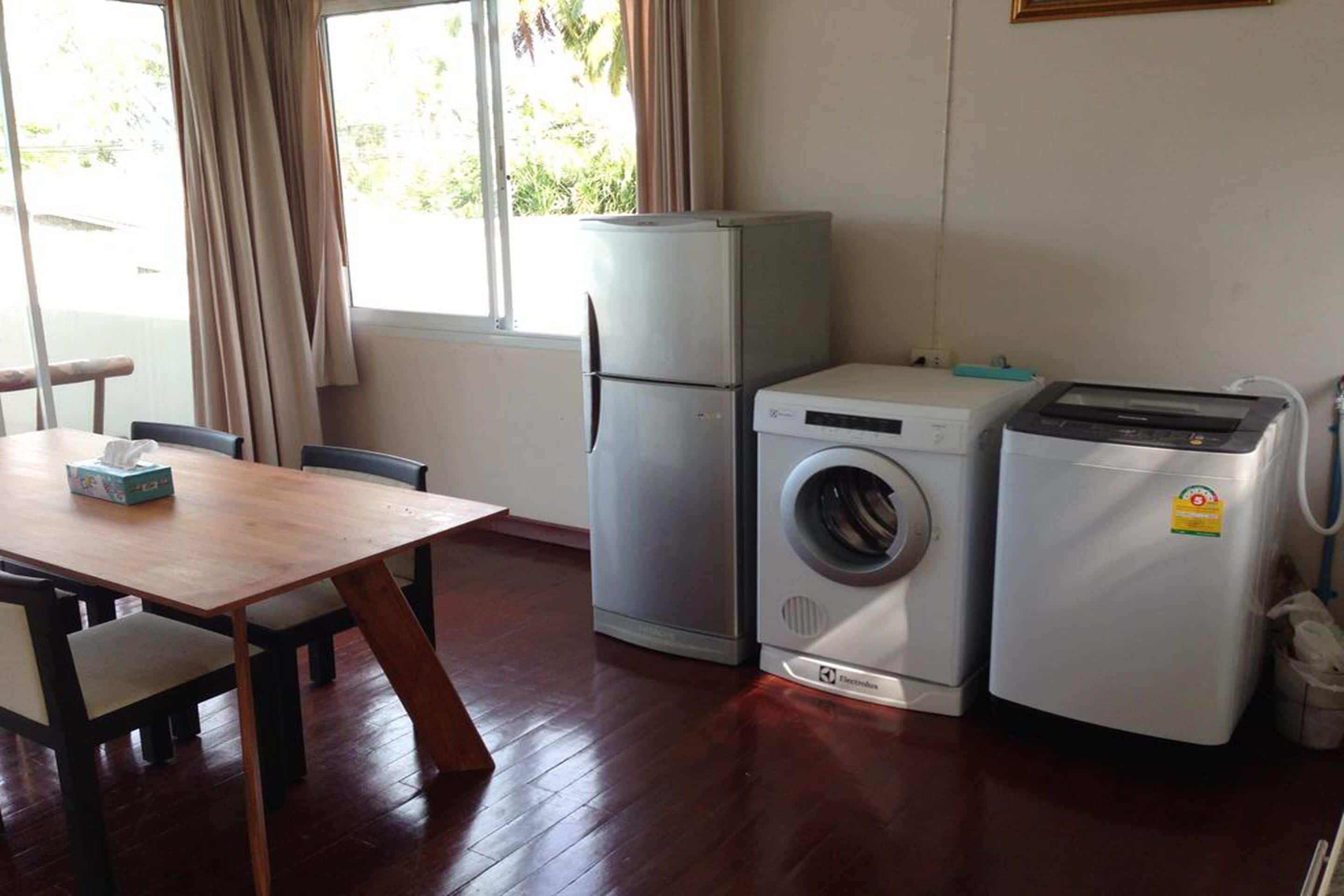 Una cocina compacta con refrigerador, lavadora y una mesa con sillas.