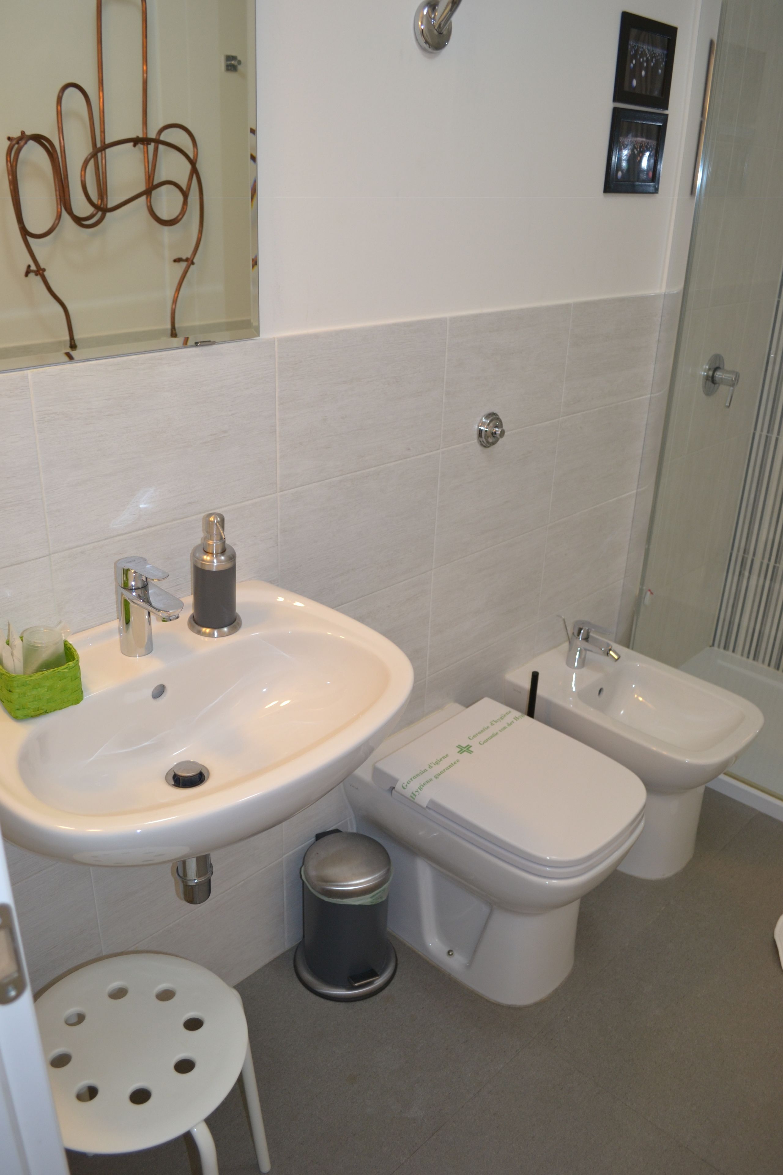 Une salle de bain équipée d’un lavabo, d’un bidet, de toilettes et d’un petit tabouret.