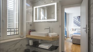 A modern bathroom with a large mirror, a sink, and a glass shelf. - Luxury rooms Paula (Split)